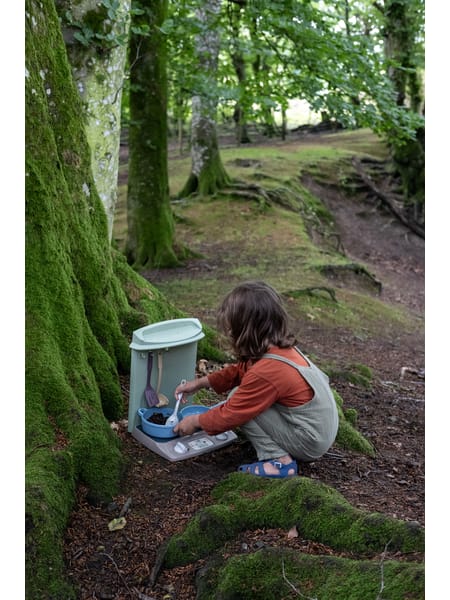 Mintgrøn køkkenboks med skeer og tallerkener på beige underlag.